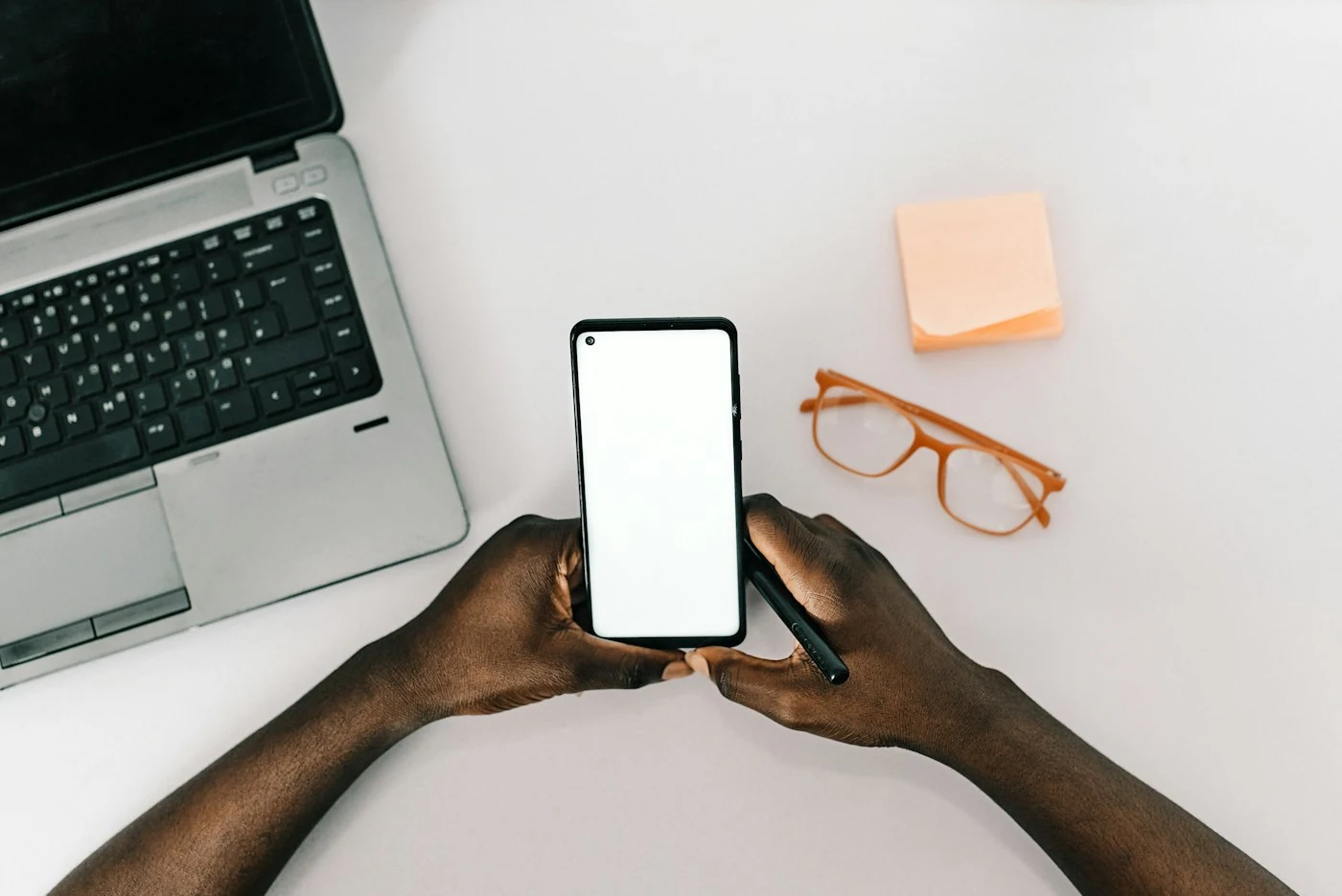 Une personne tient un téléphone au-dessus d’un bureau